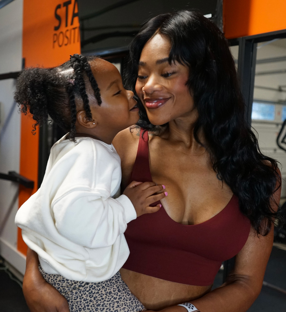 The coach is smiling while looking at her daughter.